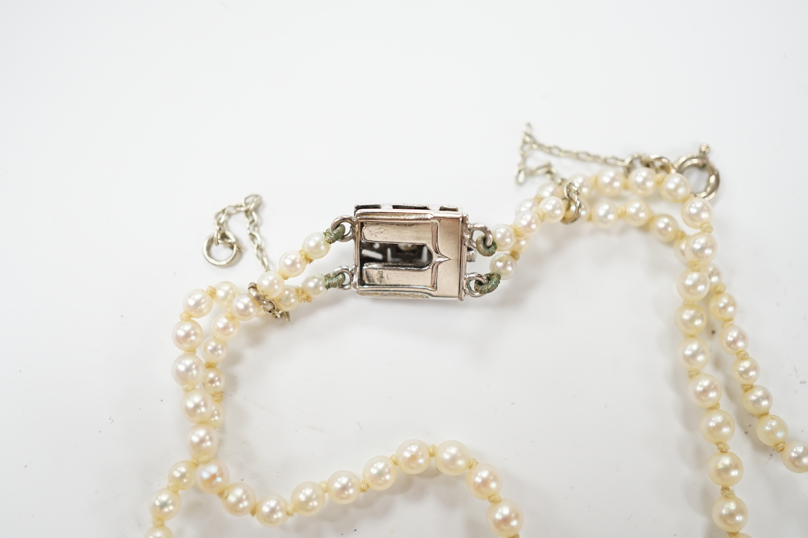 A 1940's French double strand graduated cultured pearl necklace, with diamond set white metal clasp (18ct poincon mark), 46cm.